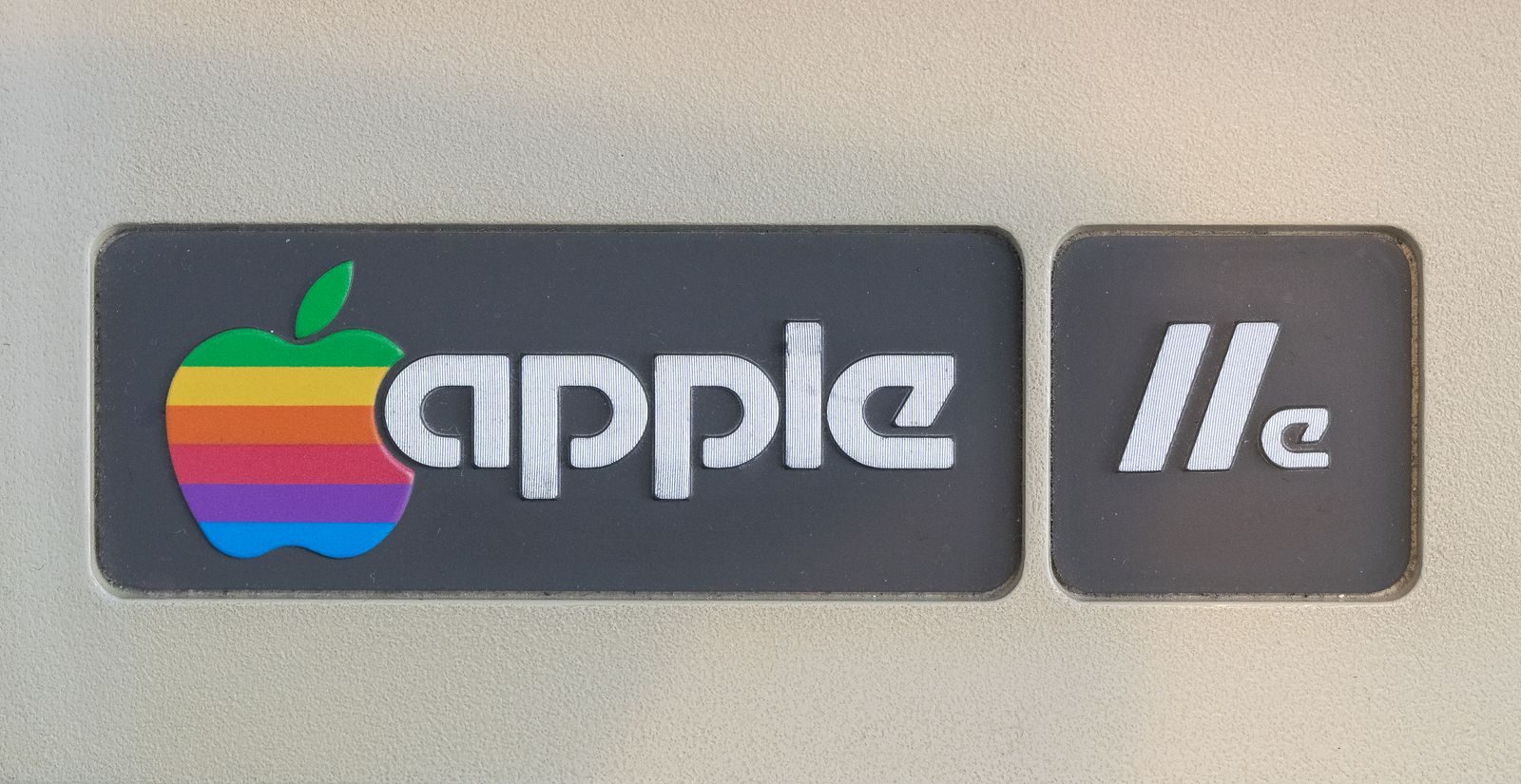 Close-up of retro Apple IIe computer logo featuring rainbow apple symbol, showcasing vintage technology design.