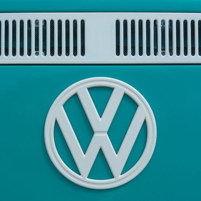 Close-up of a vintage Volkswagen emblem on a teal van, showcasing classic design and color.