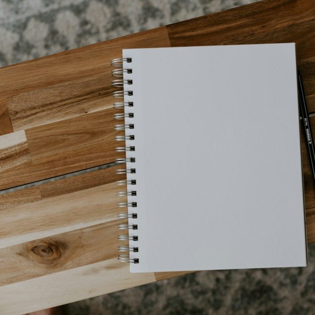 white spiral notebook on brown wooden table