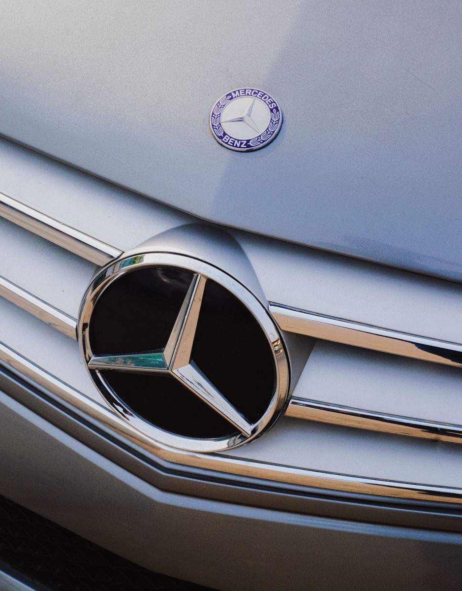 Detailed shot of a luxury car's front grille with emblem, showcasing design elegance.