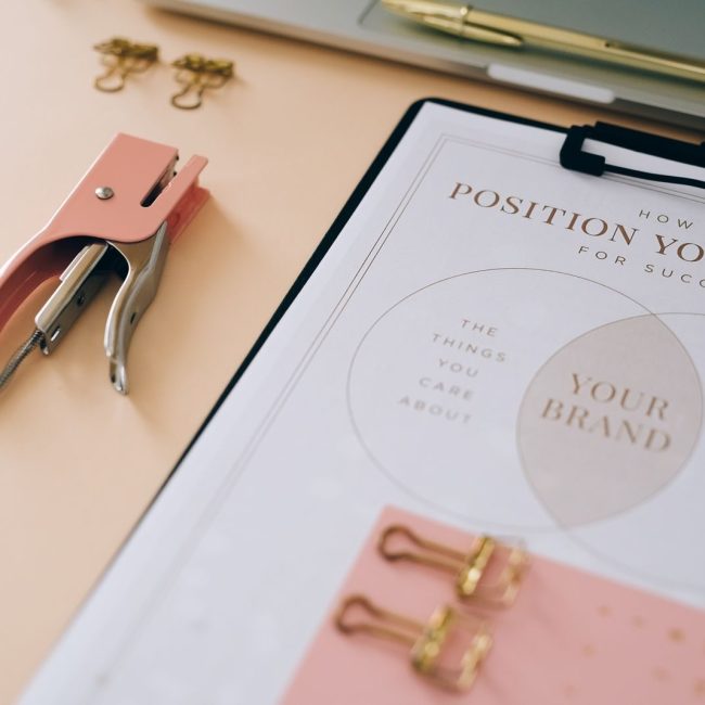 Pink stapler and branding document on a desk showcasing stylish office setup.